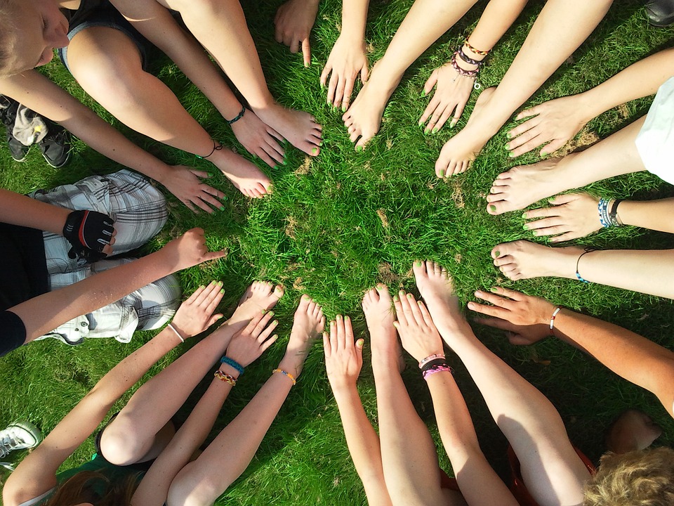 Hände und Füße bilden einen Kreis auf grüner Wiese - Nachhaltige Geldanlage