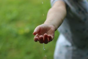 Kinderhand fängt Wasserstrahl