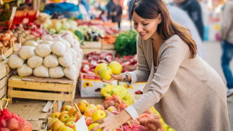 Eine lächelnde Frau sucht Obst am Markt aus - Fonds anhand von Obstsorten erklärt