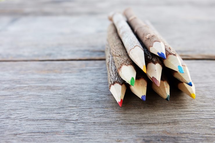 Buntstift mit Holzrinde liegen auf einer Holzplatte. Nachhaltige Veranlagungen