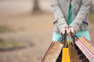 Viele Einkaufstaschen in der Hand einer Frau - Spartipps gegen den Konsumrausch