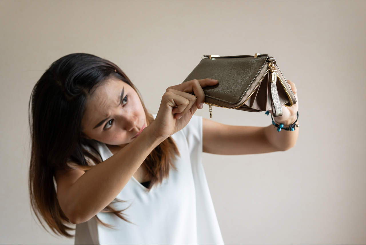 Frau hält leere Geldbörse in die Höhe, sie braucht wohl Spartipps.