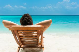 Mann im Liegestuhl macht All Inclusive Urlaub mit Meerblick