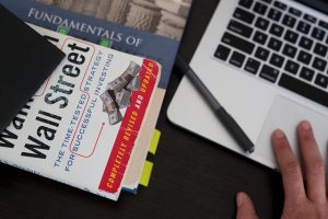 Macbook mit Stift und Buch über Wallstreet - Mein Leben als Fondsmanager
