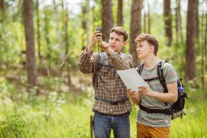 Etwas Neues ausprobieren im Zuhause-Urlaub - 2 junge Männer beim Geocaching im Wald 