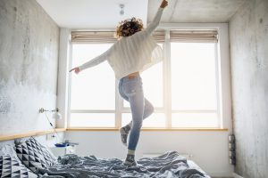 Frau tanzt auf ihrem Bett - ein unvergesslicher Urlaub zuhause