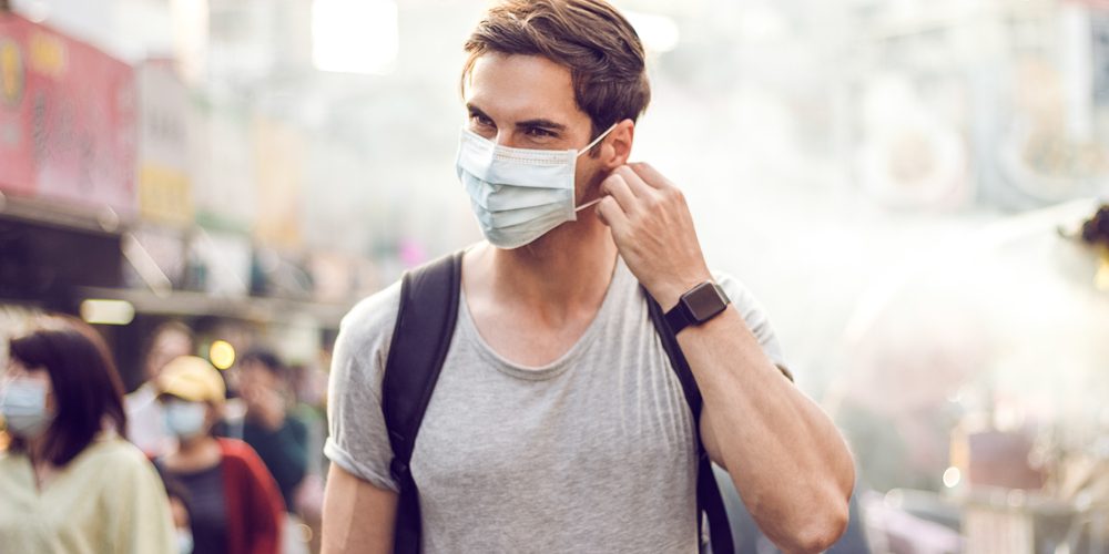 Optimismus durch Entspannung bei Pandemie - Mann mit Covid-19-Maske auf der Straße