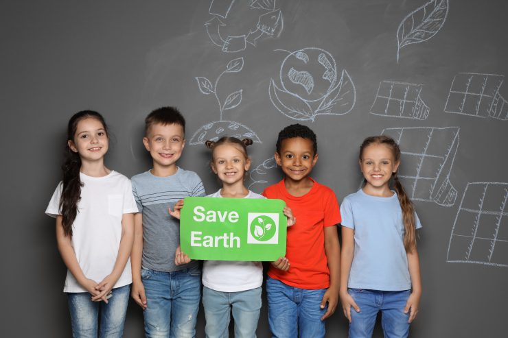 Fünf Kinder halten das Bild "Save Earth" hoch. Klimaneutrale KAG.