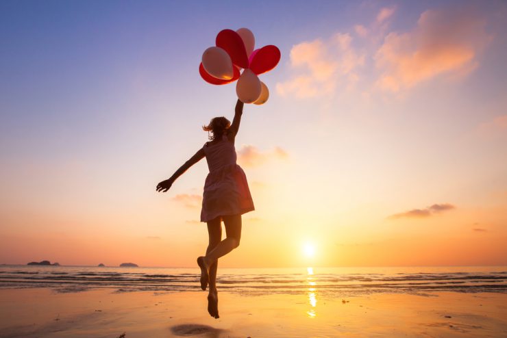 Frau springt mit Luftballons am Strand - 8 Fragen zur schnelleren Umsetzung Ihrer Wünsche