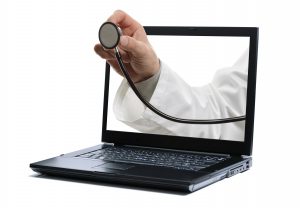 Eine Hand mit Stethoskop greift durch den Bildschirm eines Laptops - Telehealth.