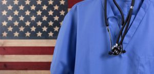 Arzt steht vor USA Flagge: Das Gesundheitssystem spielt in beiden Wahlprogrammen eine große Rolle
