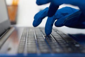 Behandschuhte Hände auf Laptop - Cyber Security wächst