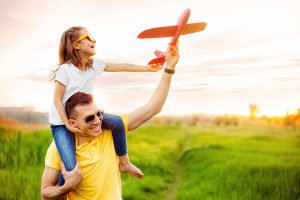 Mann spielt Flieger mit Kind - durch Fokus auf Finanzen Geld vermehren