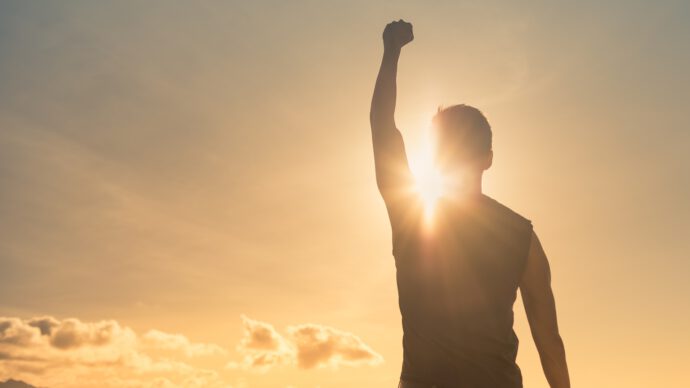 Mann mit Hand hoch im Sonnenuntergang - Tipps für Erfolg