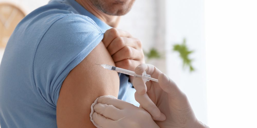 Mann im blauen T-Shirt wird geimpft - Ist der Sputnik Impfstoff besser als gedacht?
