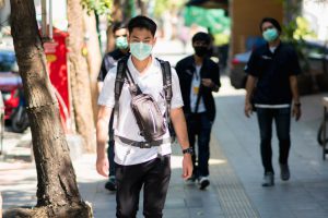 Chinese mit Maske spaziert in der Stadt - der China Markt wächst nach der Corona Pandemie stark
