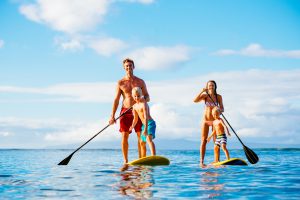 Familie steht am Stand Up Paddle