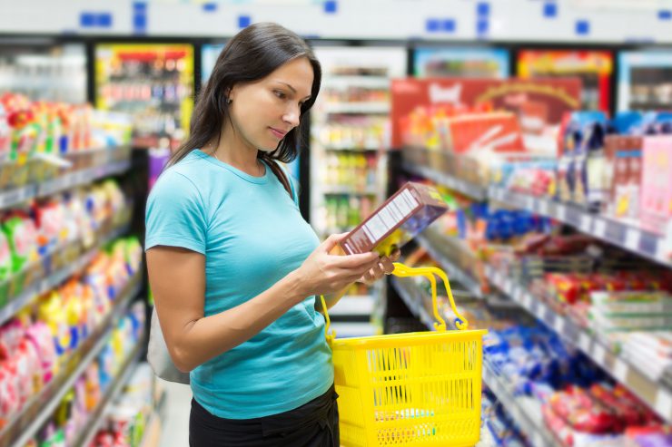 Frau im Supermarkt prüft die Zutaten auf einer Verpackung