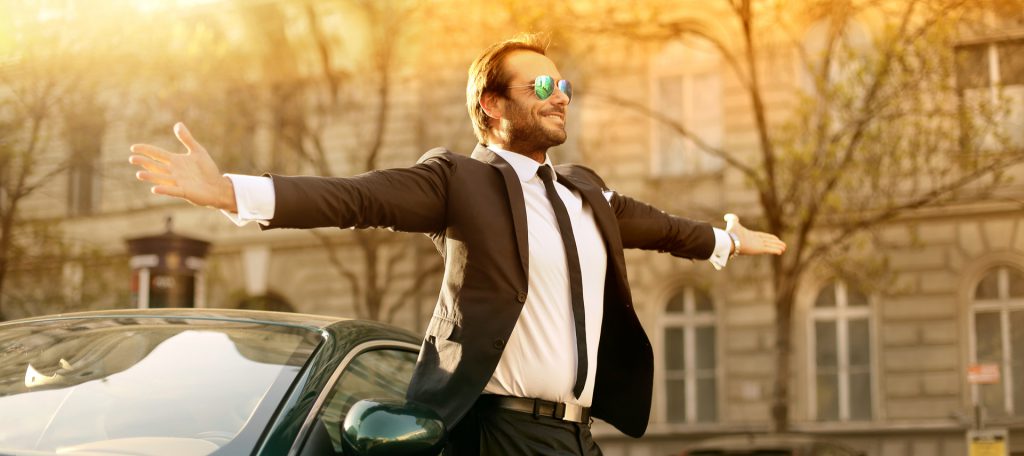 Ein reicher Mann mit Sonnenbrille und Auto: Geld-Vorurteil: Reiche Menschen verdienen ihr Geld unredlich