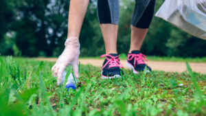 Eine Frau hebt Müll beim Laufen auf - Plogging als neues beliebtes, nachhaltiges Hobby