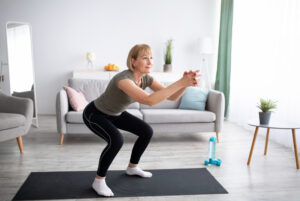 Frau macht Kniebeuge auf einer Yogamatte