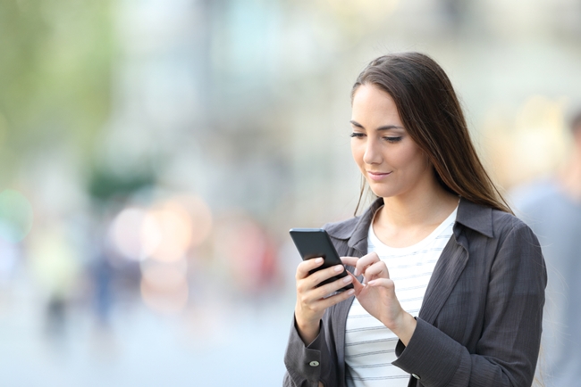 Eine Frau der Gen Z blickt aufs Handy und überprüft ihre Finanzen