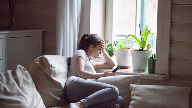Eine Frau Gen Z liegt auf der Couch und betreibt Doomscrolling