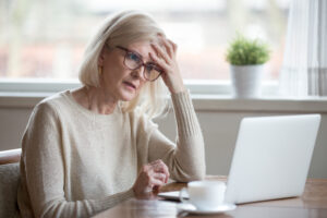 Frau blickt sorgenvoll auf den Laptop - wie du Altersarmut bekämpfen kannst