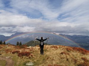 Frau mit Weitblick vor dem Regenbogen am Berg - was eine langfristige Denkweise bringt