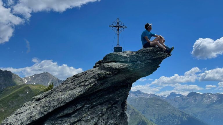Ein Mann sitzt am Gipfel eines Berges - Aktien im Aufwärtstrend.