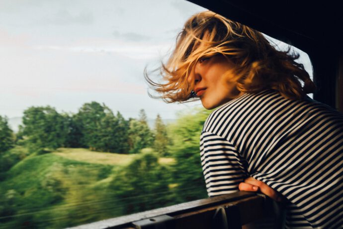 Frau blickt aus dem Zug und überlegt, nachhaltig leben, wieviel bringt das?