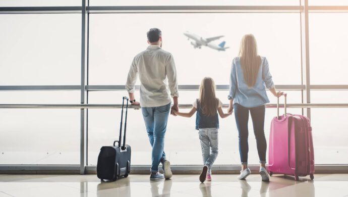 Eine Familie steht am Flughafen - Reisen heuer voll im Trend