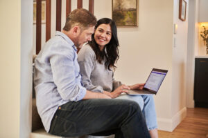 Mann und Frau lächelnd vor dem Laptop - überlegen Fondssparen