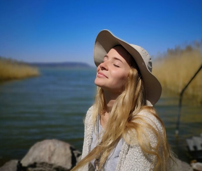 Eine Frau mit Hut blickt entspannt in den See - Steuern sparen für Selbstständige
