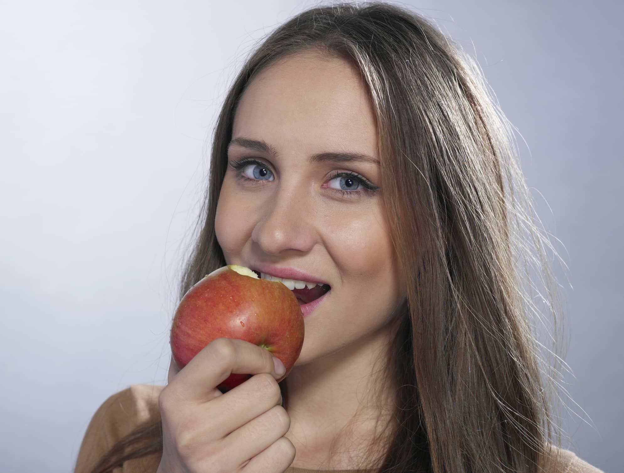 Eine hübsche brünette Frau beißt in einen Apfel ihrer Gesundheit willen