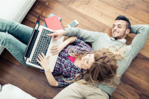 Eine Frau und ein Mann liegen am Boden mit dem Laptop
