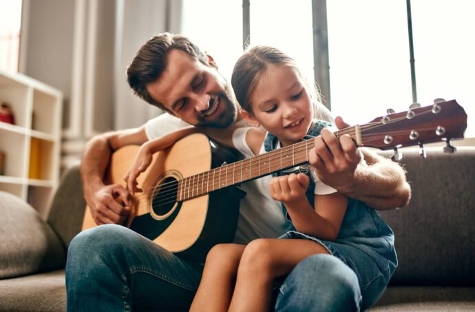 Mann mit einem Mädchen, das Gitarre spielt - für Kinder rechtzeitig vorsorgen