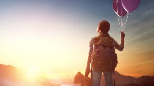 Ein Kind mit Luftballon blickt gen Himmel - vorsorgen für Kinder