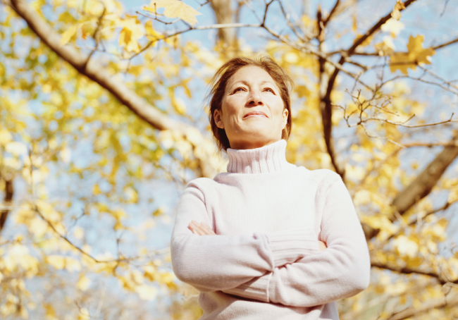 Eine Frau im Herbst in der Phase der Wechseljahre schaut auf sich