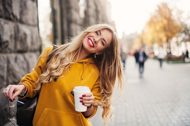 Eine strahlende junge Frau mit Kaffee in der Hand und viel Frauenpower