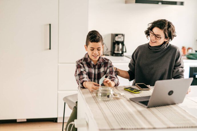 Eine Frau erklärt ihrem Sohn finanzielle Bildung am Laptop