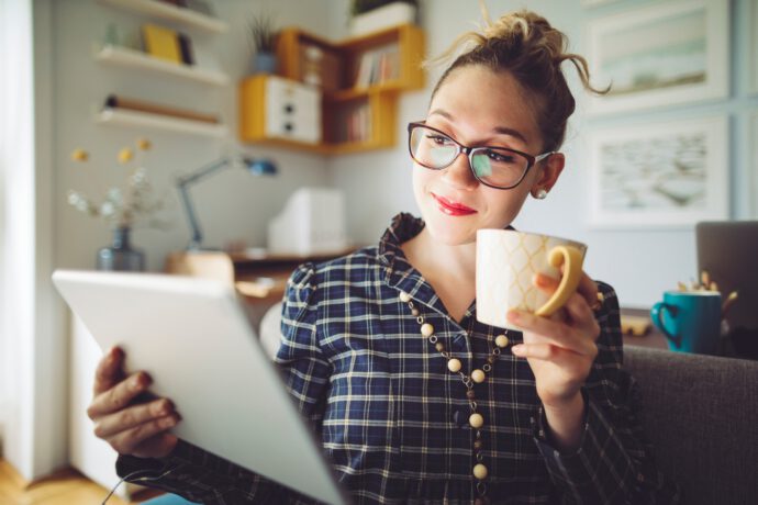 Eine junge Frau, Gen Z, zu sehen, mit Laptop und Kaffee, die für ihre finanzielle Zukunft vorsorgt.